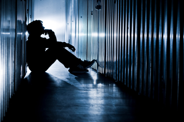 Teenager sitting in dark hallway