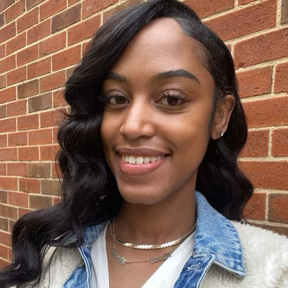 Headshot of Jatoia Potts wearing jean jacket in front of brick wall