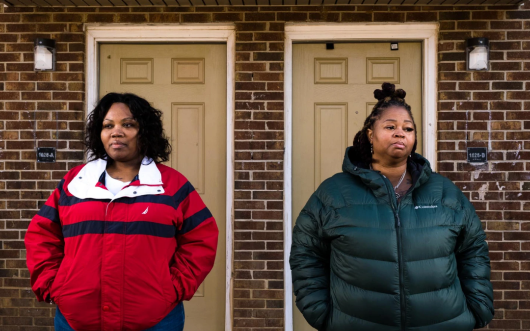 Two Black women wearing jackets, Yolanda Irving and neighbor Kenya Walton, stand next to each other in front of the doors to their homes