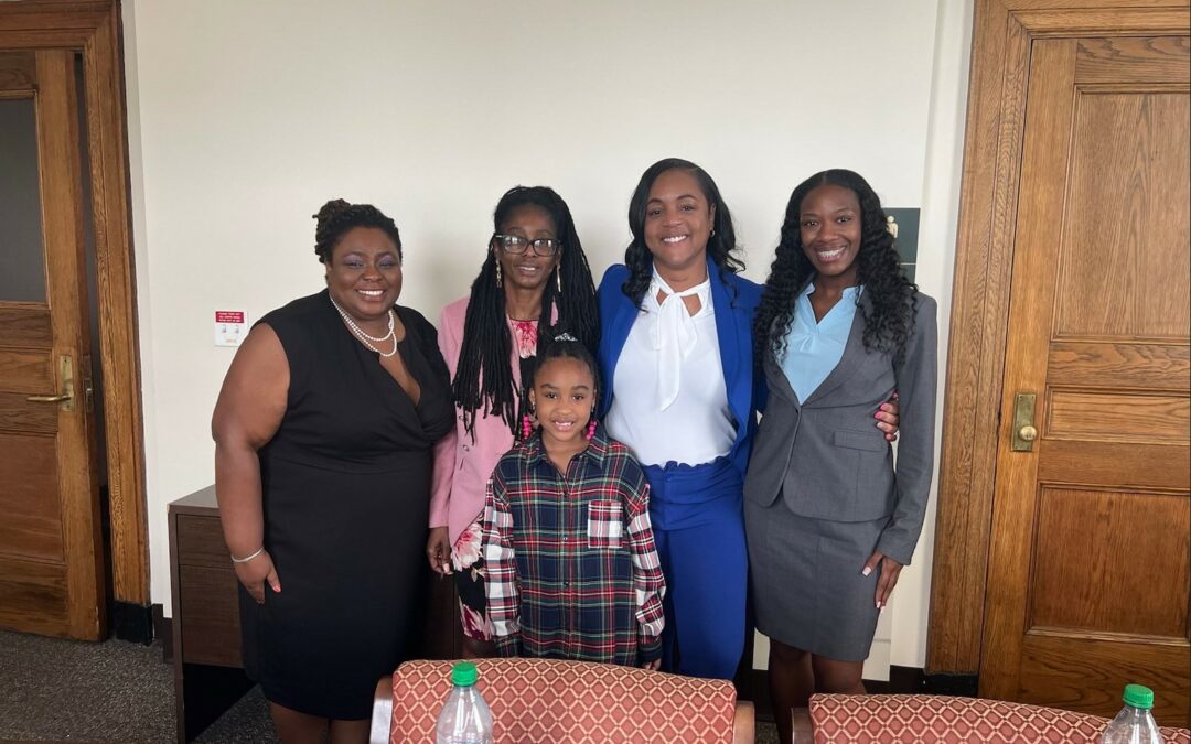 Dejuana Bigelow, a Black woman, stands with her Black women lawyers and daughter